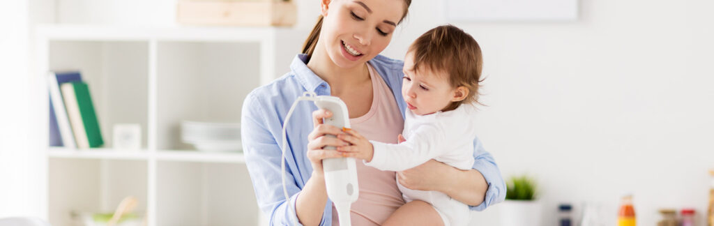 Mother holding toddler in her arms while cooking